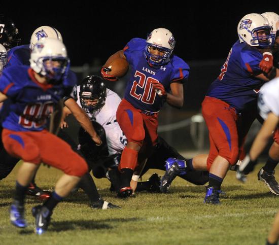 Lakes' Direll Clark (center) runs between his blockers Thomas Dubicki (left) and Ty Summers (right) on a 37-yard run. | Michael Schmidt~Sun-Times Media