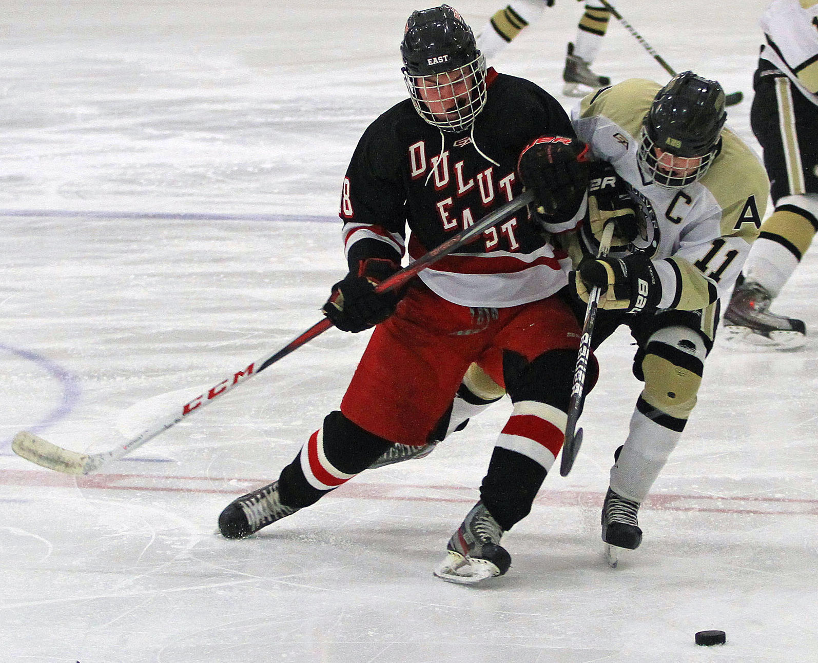 Duluth East's Wyatt Irwin leans into Andover's Brady Barthold as they chase the puck. Photo by Dave Madsen, www.facebook.com/spbdm