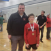 Freshman Deacon Ramthun poses with Coach Wardlow donning his third-place state medal.