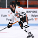 Sarah Fillier, Princeton forward, skates down the ice with an orange C on her chest, in the Princeton white and orange jersey.