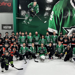 Group Picture of the adaptive hockey on-ice event. They are wearing Victory Green Dallas Stars jerseys and black and orange jerseys as they pose for a picture on the ice. 