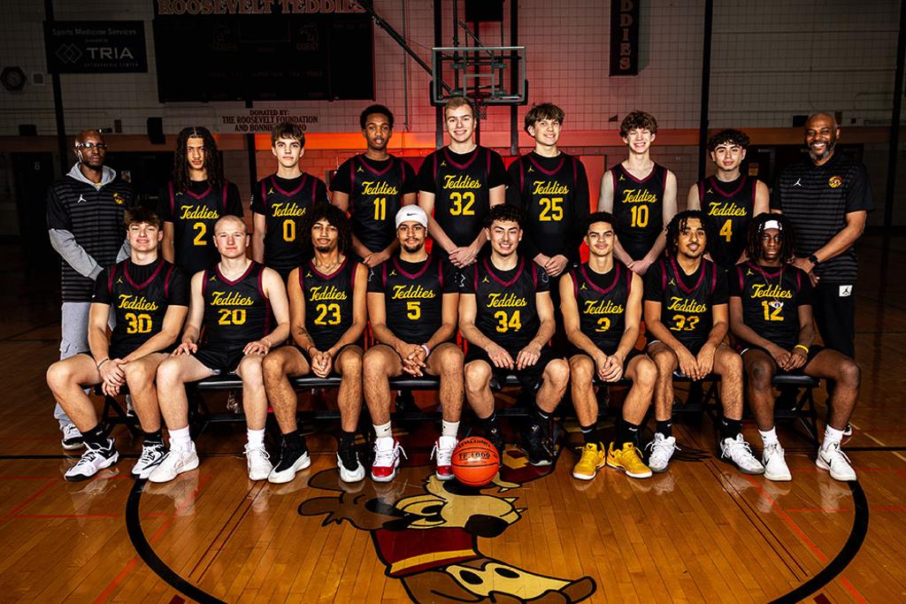 Minneapolis Roosevelt Boys Varsity team pose in a darkly lit Jack Wells Gymnasium